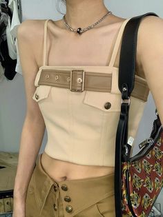 Woman in a beige crop top and brown pants with a shoulder bag