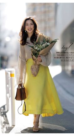 Woman in a yellow skirt and knitted top holding a bouquet outdoors