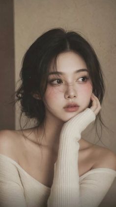 Woman with black hair wearing an off-shoulder top, looking away