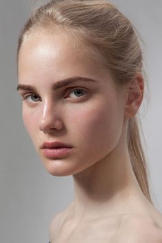 Blonde woman with a ponytail and bare shoulders in a studio portrait