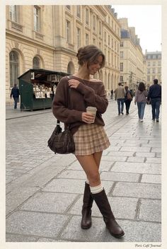 Woman in a plaid skirt and brown sweater on a city street