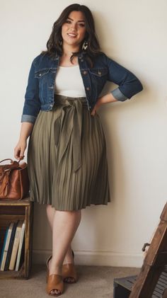 Woman in a denim jacket and pleated skirt posing indoors