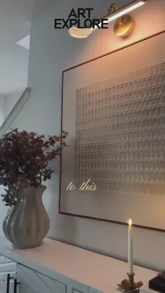 Indoor scene with wall art, a vase with plants, and a lit candle