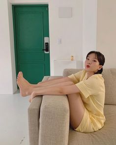 Woman in yellow pajamas sitting on a couch with her feet up