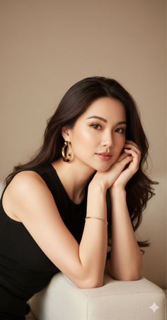 Woman with long dark hair and gold jewelry posing indoors