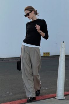 Woman in sunglasses and wide leg pants walking outdoors