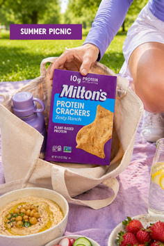 Hand placing a box of protein crackers into a bag during a summer picnic