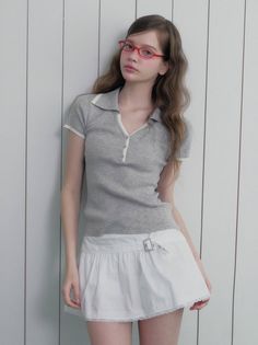 Woman with long hair and red glasses wearing a polo shirt and mini skirt