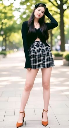 Woman in a black cardigan and plaid skirt posing outdoors