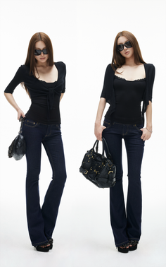 Two women in black tops, dark wash jeans, and sunglasses posing with handbags