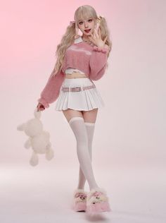Woman with blonde pigtails in a pink sweater and white pleated skirt holding a teddy bear