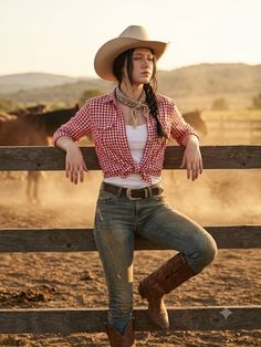Woman in a cowgirl hat and plaid shirt leaning on a fence at golden hour