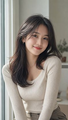 Woman with long dark hair wearing a ribbed top, smiling indoors