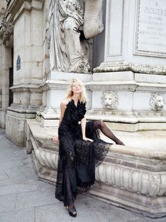 Woman in a black dress and polka dot tights sitting on a stone monument