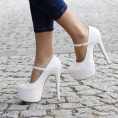 Person wearing white platform mary jane high heels and jeans on a cobblestone street