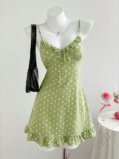 Green polka dot dress on a mannequin with a pearl necklace and black handbag