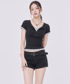 Woman in a black top and shorts with a ponytail in a studio setting