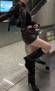 Woman in a leather jacket and mini skirt posing on an escalator