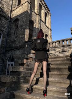 Woman with red hair in a black blazer and lace trim skirt on stone steps
