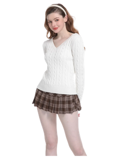 Woman in a white cable knit sweater and brown plaid skirt with a headband