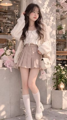 Woman in a pleated skirt and cardigan standing outdoors with soft lighting
