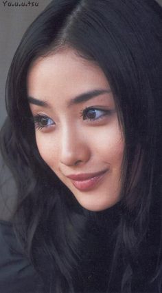 Woman with long black hair looking to the side with a soft smile