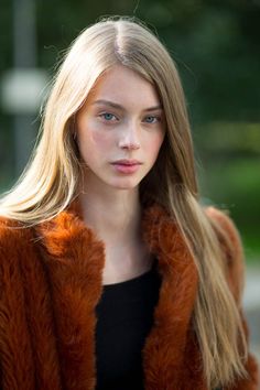 Woman with long blonde hair and blue eyes wearing a fur coat outdoors