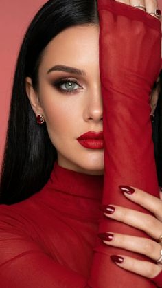 Woman with long black hair and red lipstick wearing a red sheer top