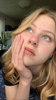 Close up portrait of a blonde woman looking up with her hand on her cheek