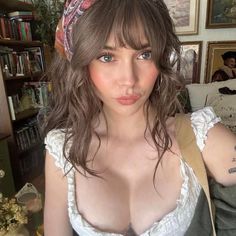 Woman with a head scarf and white top showing cleavage indoors
