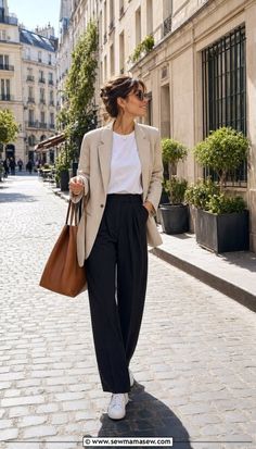 Woman in a blazer and wide-leg pants walking on a cobblestone street