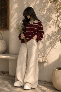 Woman in a striped sweater and corduroy pants holding flowers outdoors