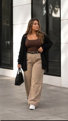 Woman with long hair wearing a cardigan and wide-leg pants outdoors
