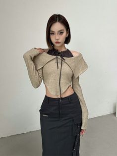 Woman with short hair and dark makeup wearing a cropped top and black skirt