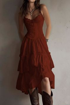 Woman in a red tiered dress and cowboy boots with long hair and jewelry