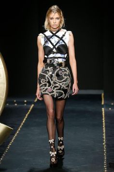Model in a black and white outfit with a harness top and embellished mini skirt