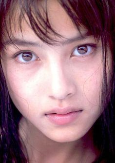 Close up portrait of a young person with dark, wet hair and natural makeup