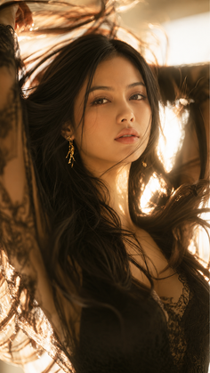 Woman with long dark hair in a lace top, backlit by golden hour light