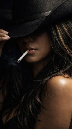 Woman in a black hat with a cigarette, dramatic lighting on her shoulder