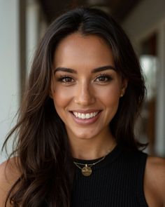 Woman with long dark hair and a nose piercing smiling at the camera