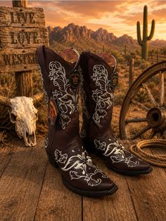 Cowboy boots on a wooden surface with a desert landscape at sunset