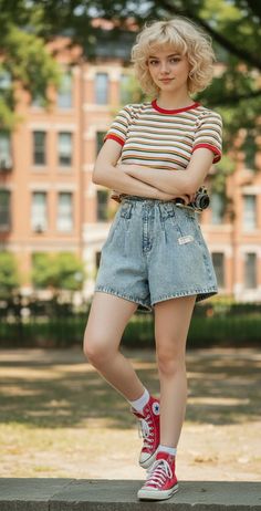 Young woman with curly blonde hair wearing a striped shirt and denim shorts outdoors