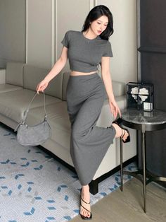 Woman in a gray crop top and maxi skirt posing indoors