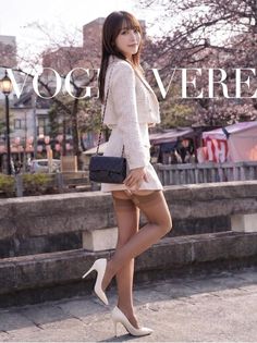 Woman in a tweed suit and stockings posing outdoors with cherry blossoms