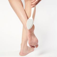Person using a pumice stone on their heel against a white background