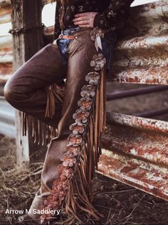 Person wearing leather chaps with floral embellishments and fringe