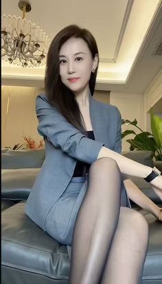 Woman in a grey business suit and black pantyhose sitting on a couch