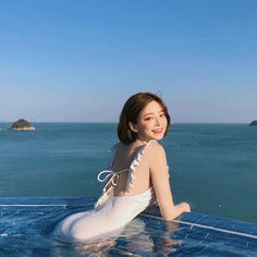 Woman in a white swimsuit in an infinity pool overlooking the ocean