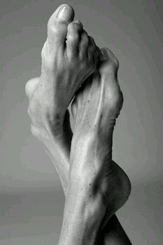 Black and white photograph of two bare feet crossed against a plain background