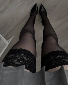 Legs in black lace-top stockings and high heels with a grey skirt